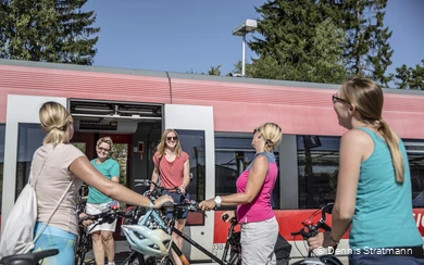 Eine Gruppe junger Frauen steigt mit ihren Fahrrädern aus dem Zug aus.