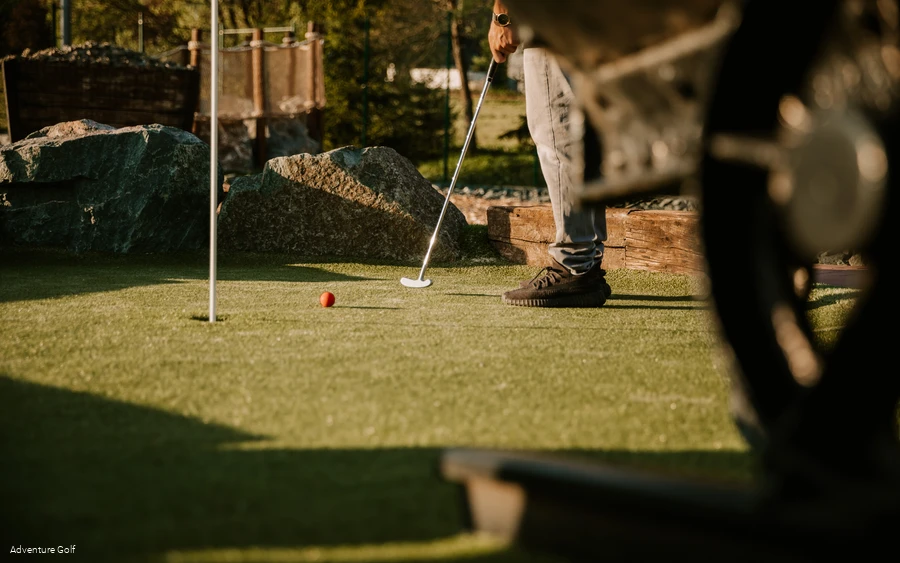 Eine Person schlägt einen Golfball Richtung Loch.