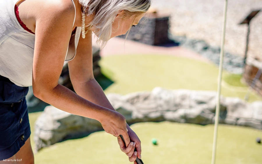 Eine Frau schlägt ihren Golfball Richtung Loch.