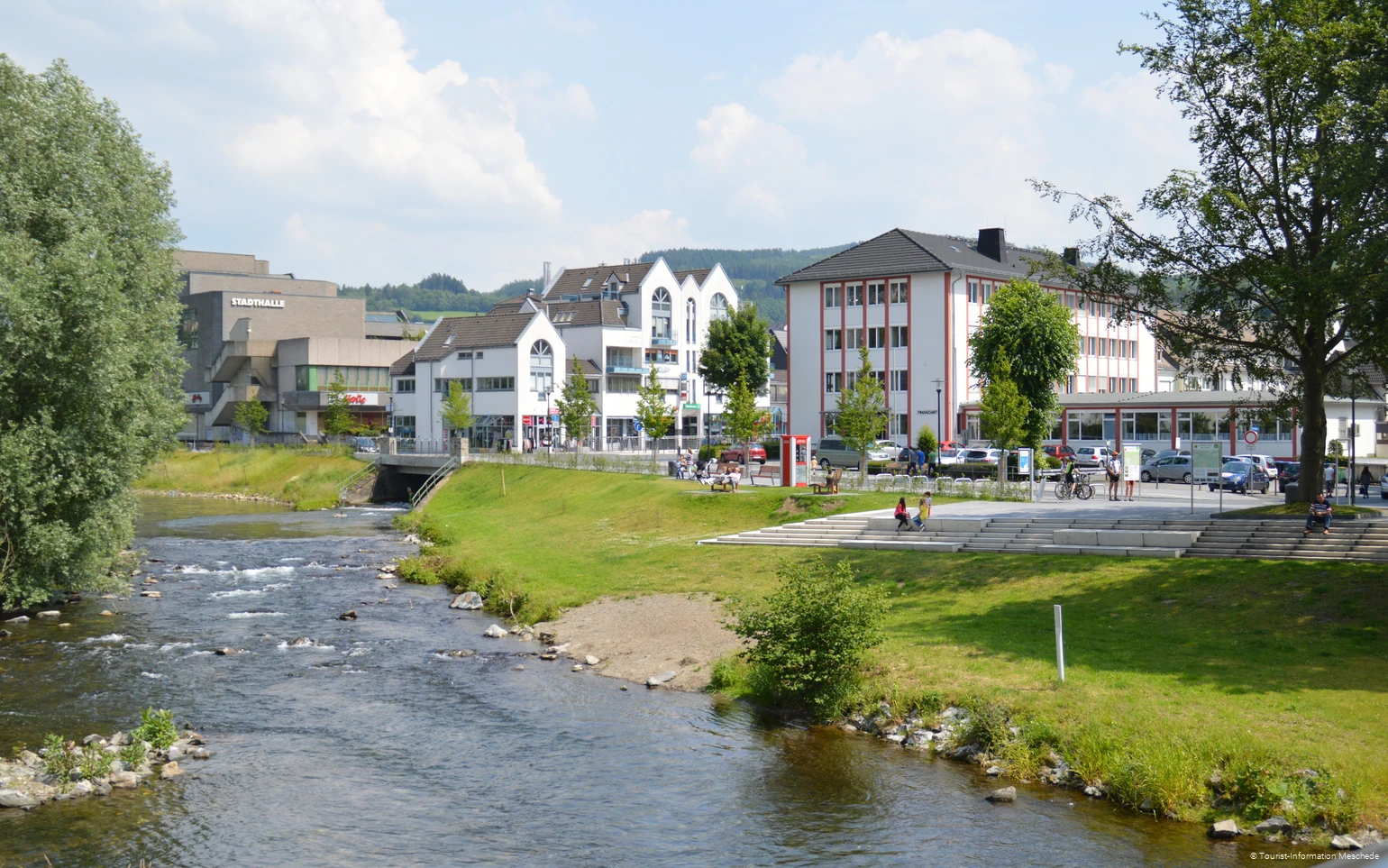 Zwei Menschen auf einer Treppe am Ufer der Ruhr. Gebäude im Hintergrund.